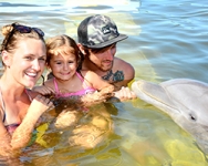 Family with a young child in the water with a dolphin